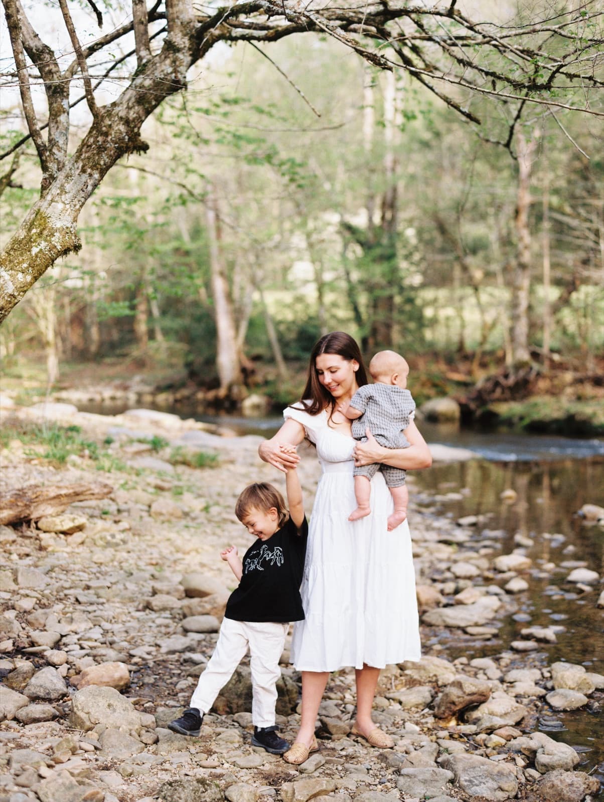 Annie Mewborn holding her two young children on a riverbank.